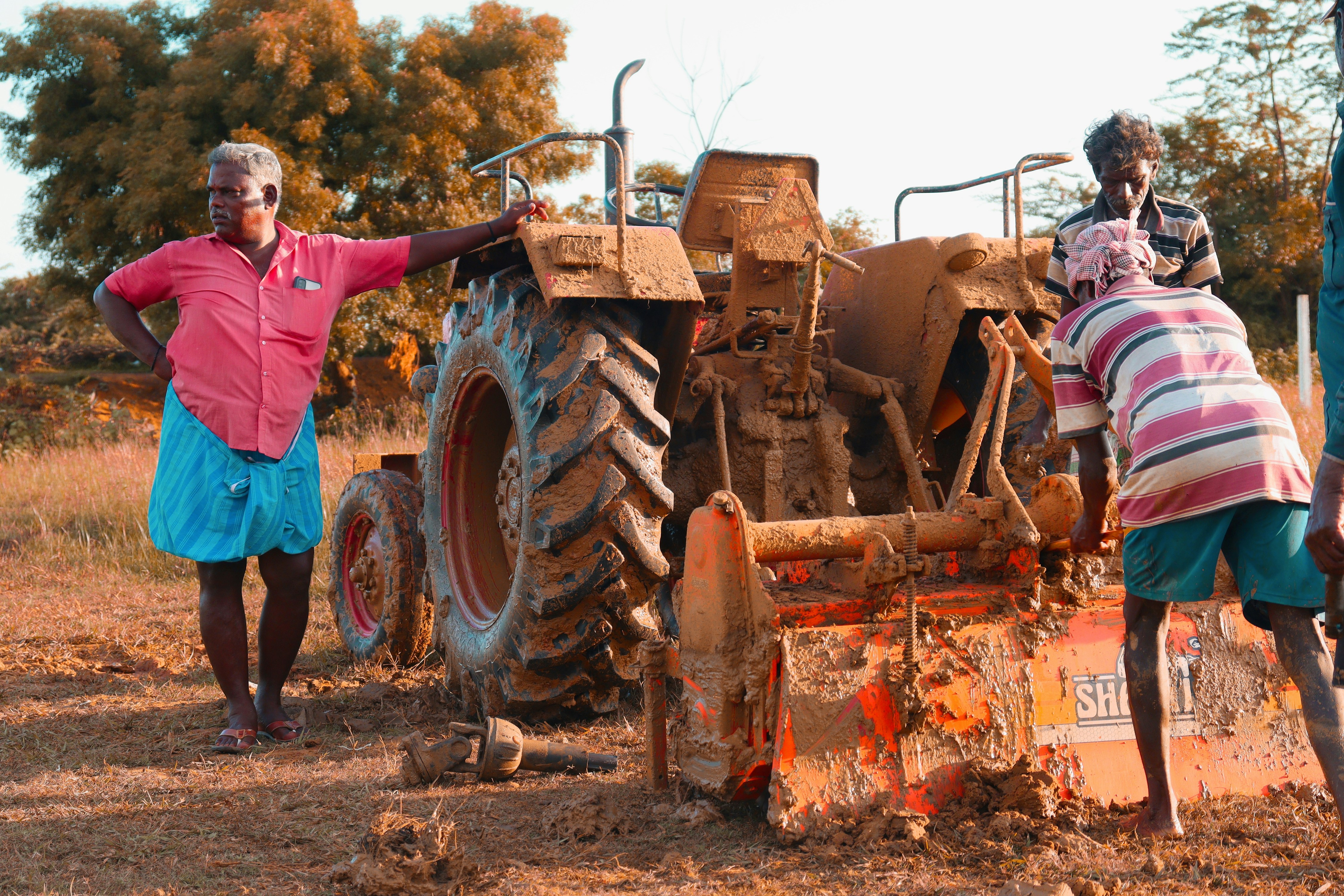 a couple of people standing next to a tractor