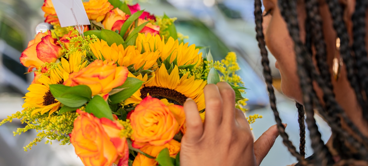 a woman is holding a bouquet of sunflowers