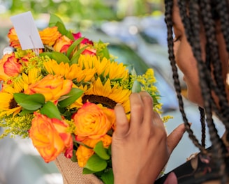 a woman is holding a bouquet of sunflowers