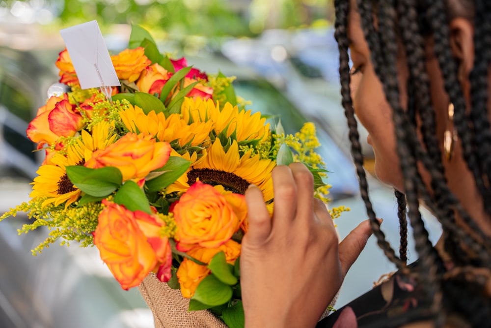 a woman is holding a bouquet of sunflowers