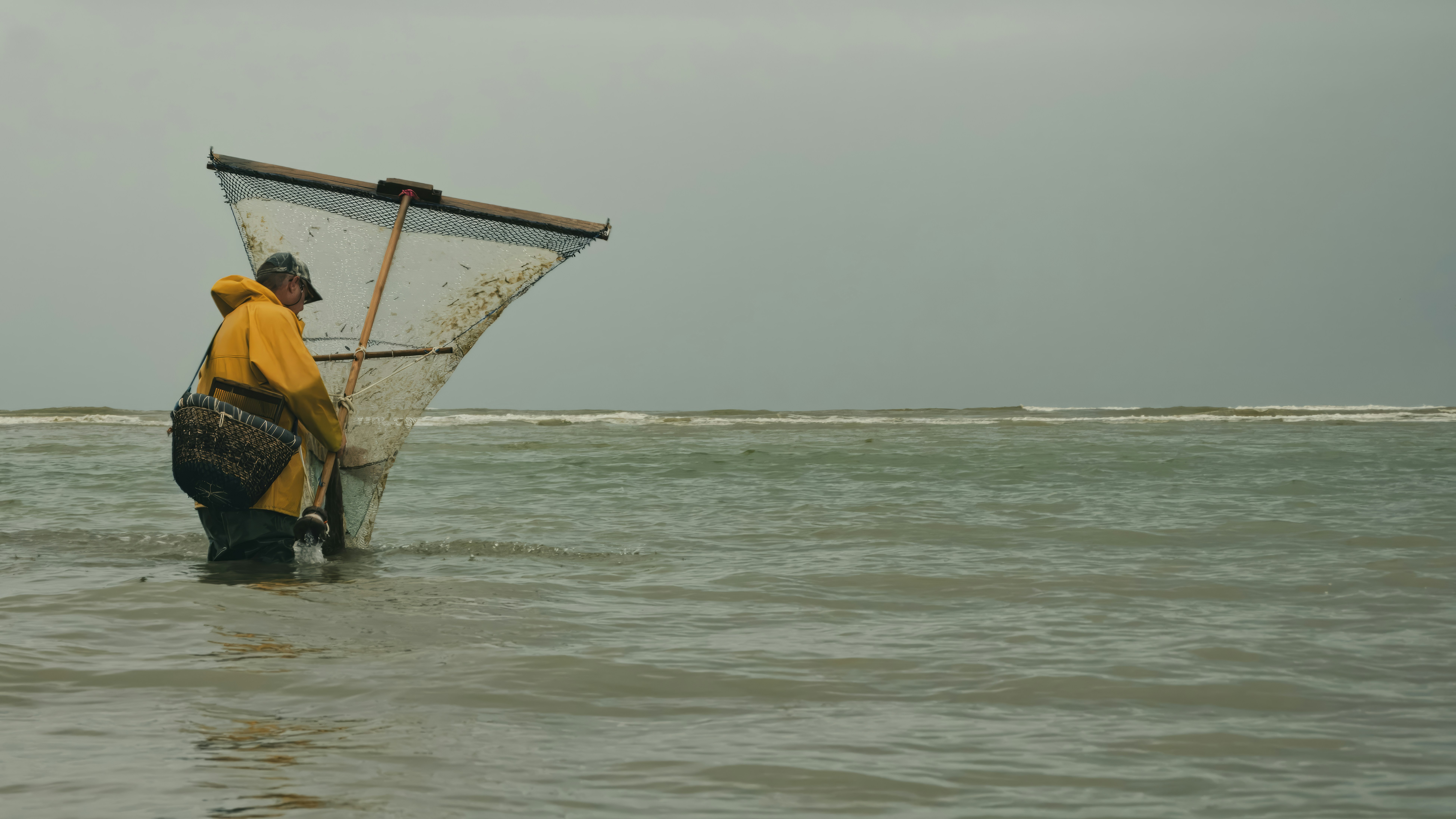 a man standing in the ocean holding a fishing net