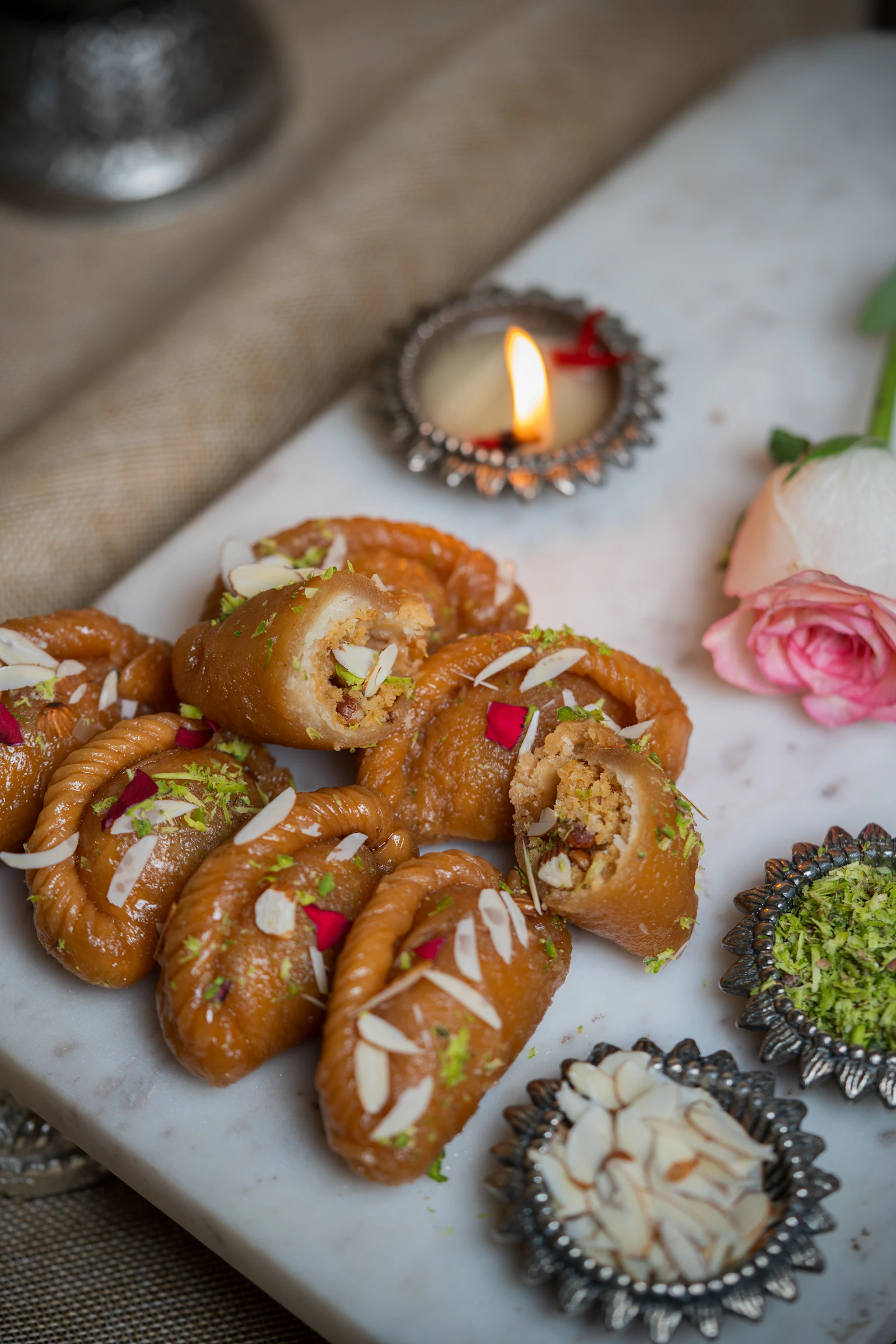 Tray of kaju katli and assorted mithai beside a festive candle