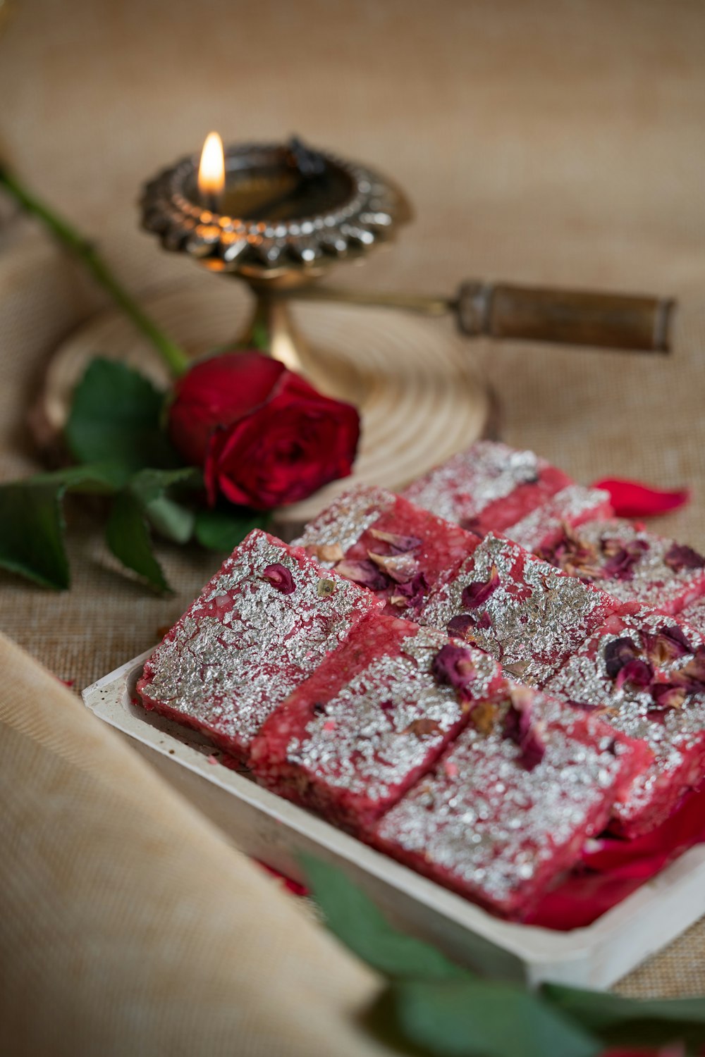 a red cake on a plate next to a candle