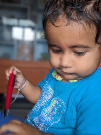 Energetic kid wearing the fairy design t-shirt, holding colorful textile markers in an urban minimalist studio.