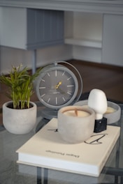 a glass table topped with a clock and a plant