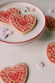 Freshly baked cookies with pastel icing shaped like hearts and stars on a vintage ceramic plate.