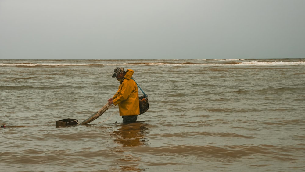 a man in a yellow jacket is wading in the water