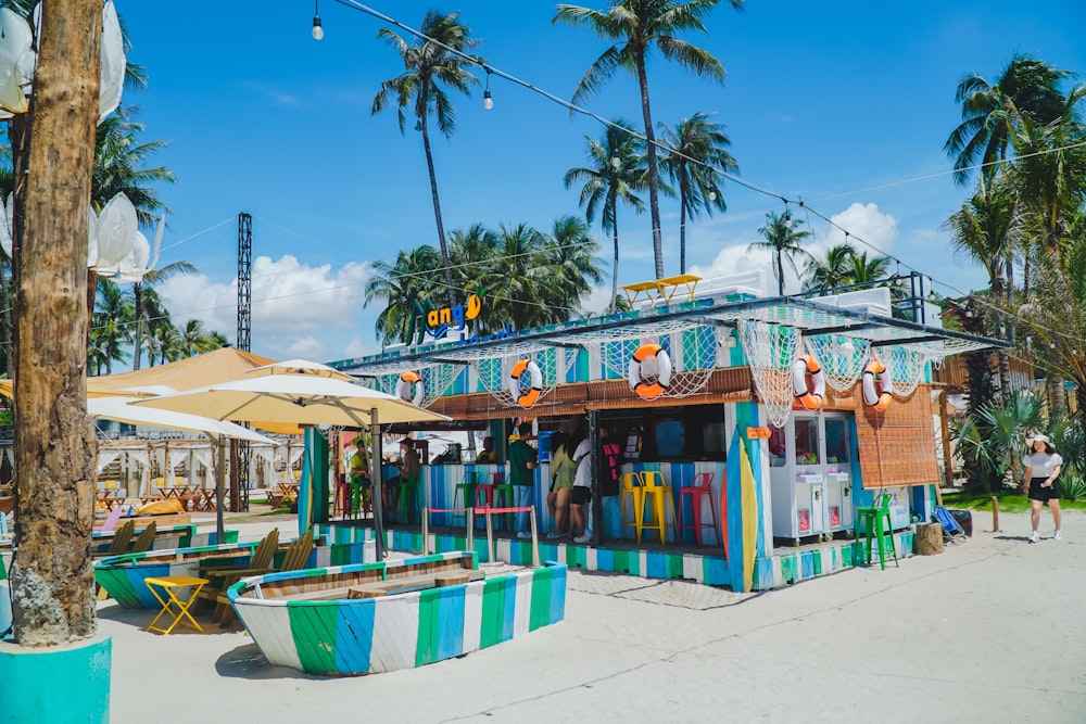 a colorfully painted building on the beach with palm trees in the background