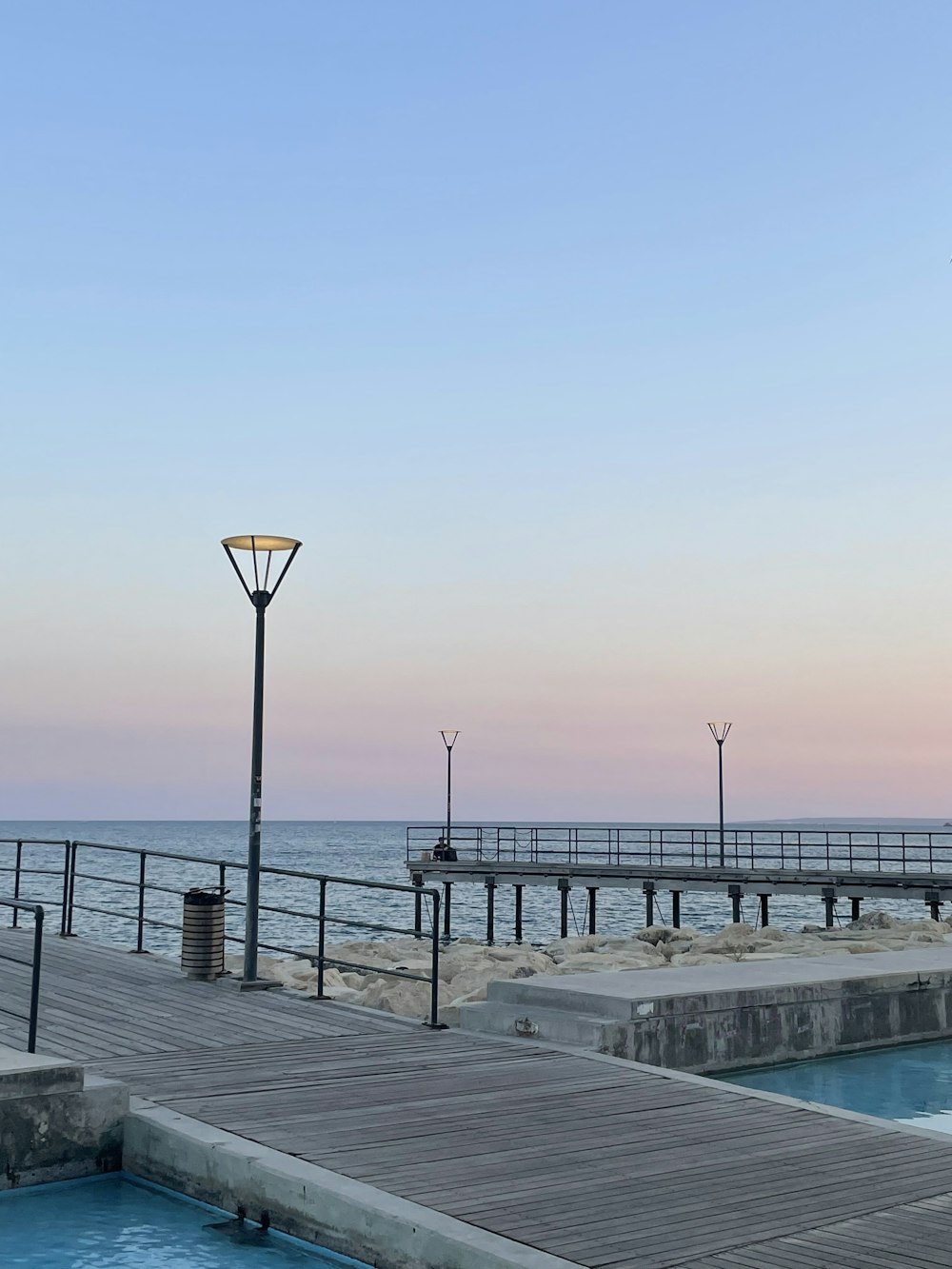 a pier with a light pole and a light pole next to a body of water