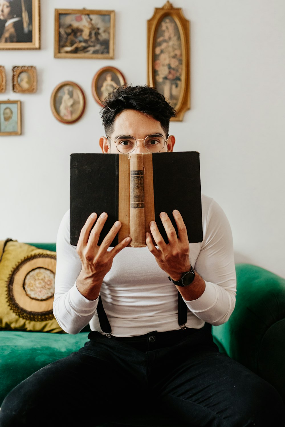 a man sitting on a green couch reading a book