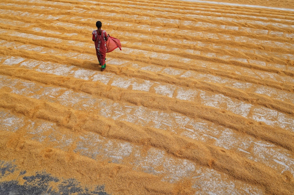 a woman walking across a field covered in dirt