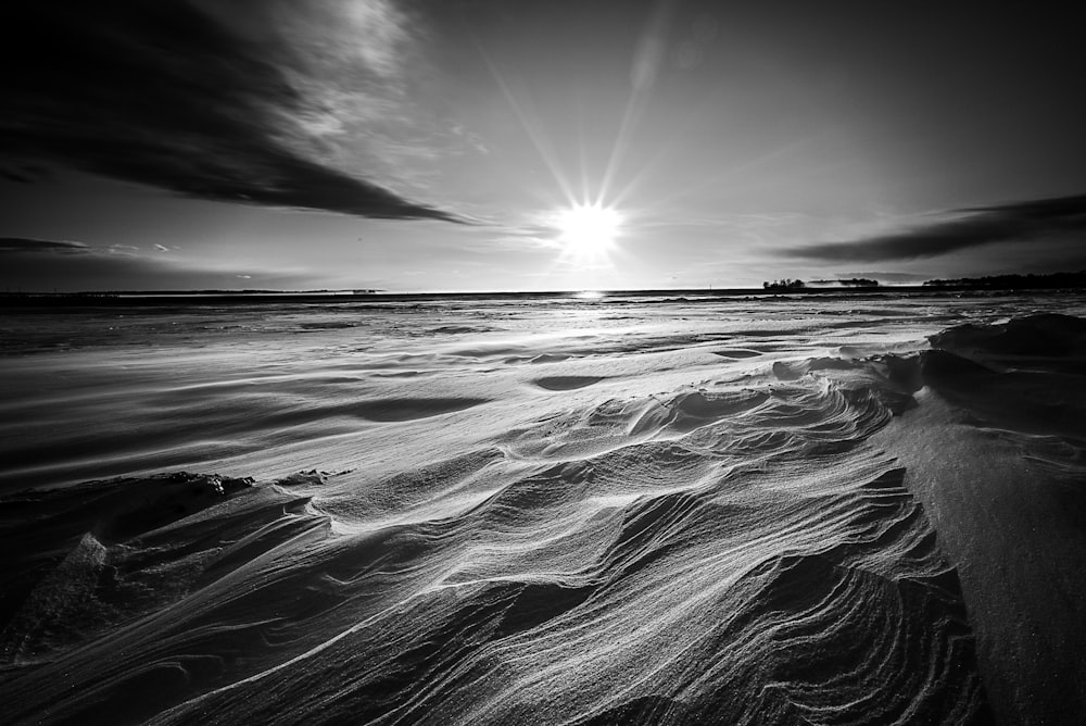 a black and white photo of the sun setting over the ocean