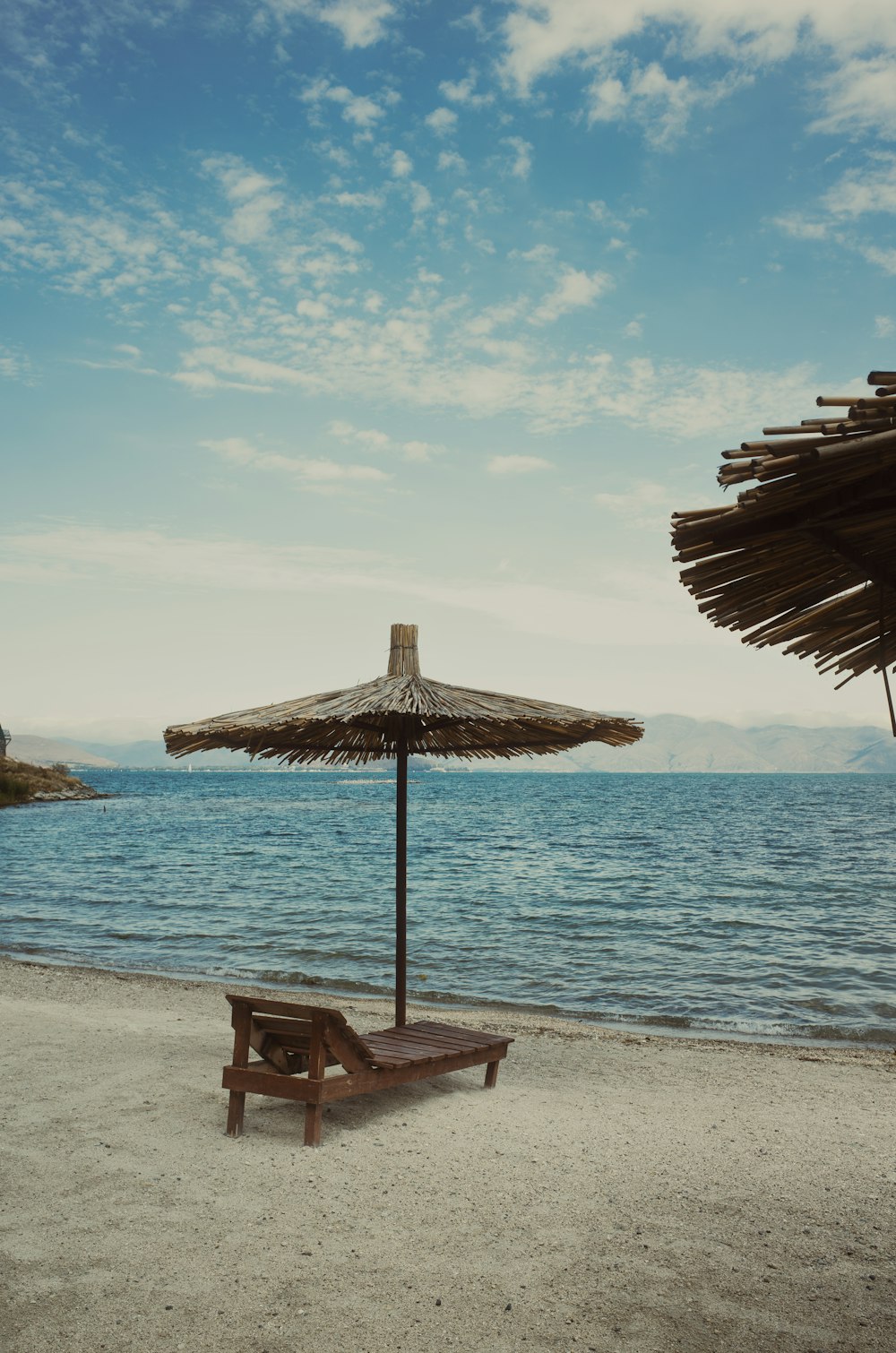 a wooden bench sitting on top of a sandy beach