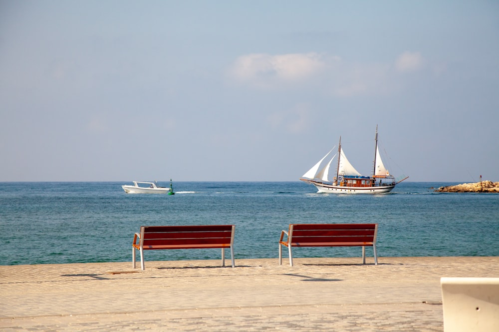 a couple of red benches sitting on top of a sandy beach