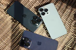 three iphones sitting next to each other on a wicker surface