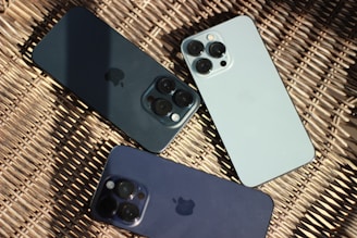 three iphones sitting next to each other on a wicker surface