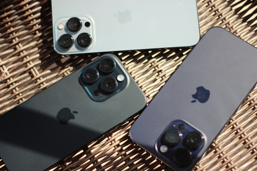 três iPhones sentados um ao lado do outro em uma mesa