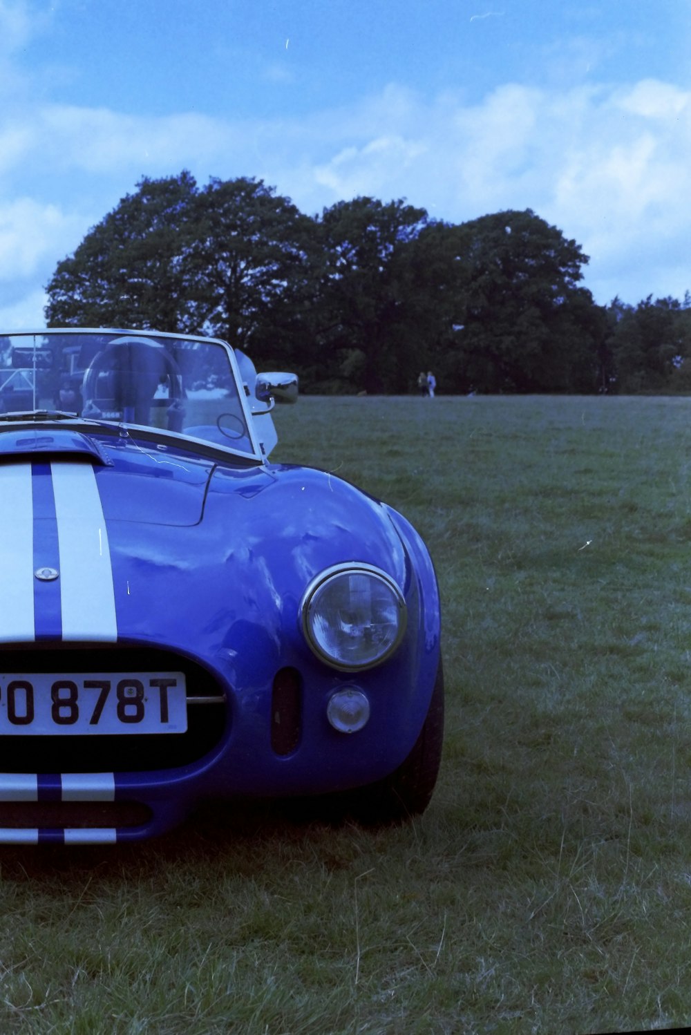 a blue sports car parked in a grassy field