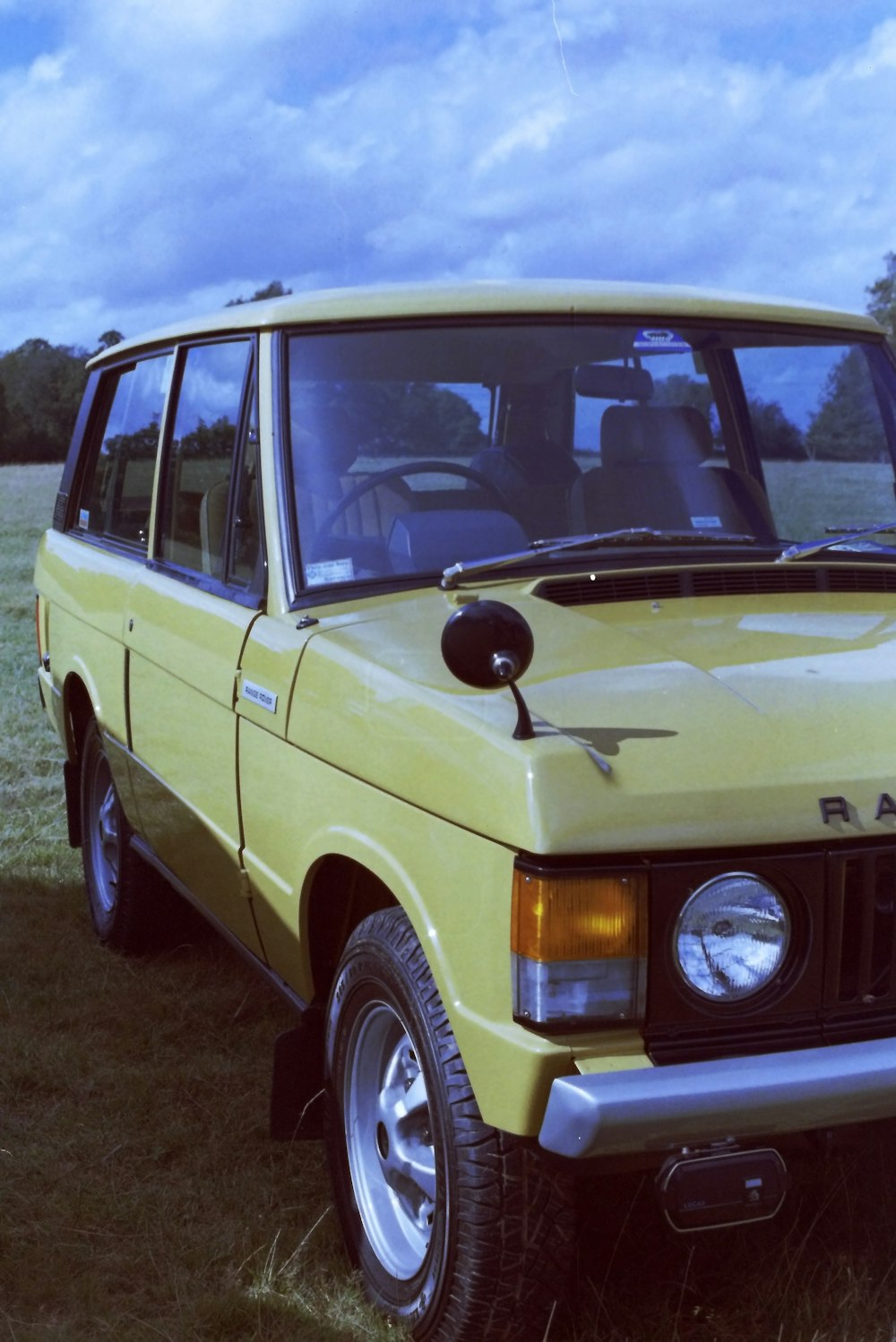 a yellow car parked on top of a grass covered field