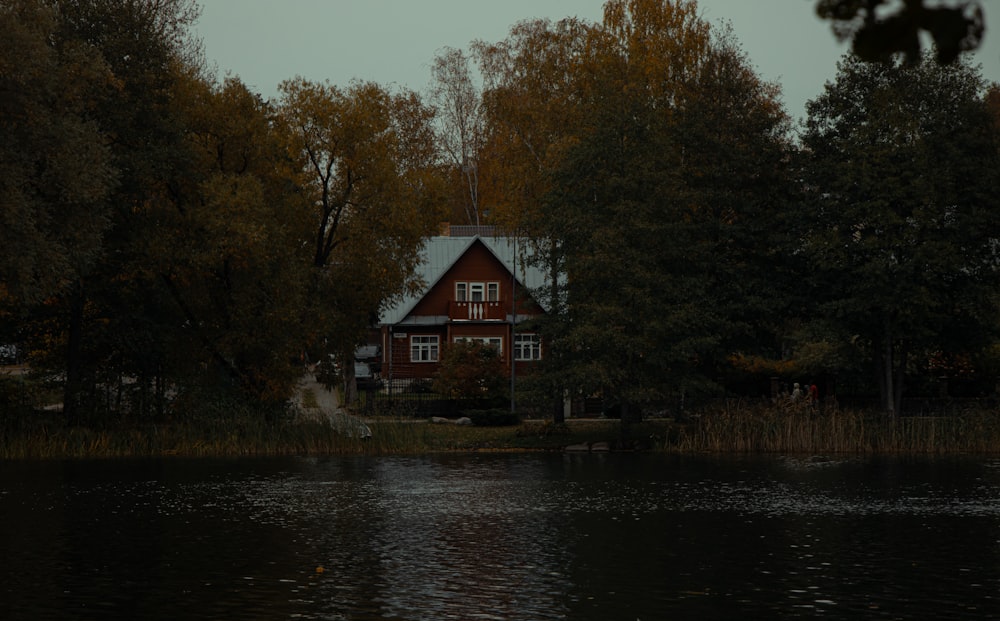 a house sitting on top of a lake surrounded by trees