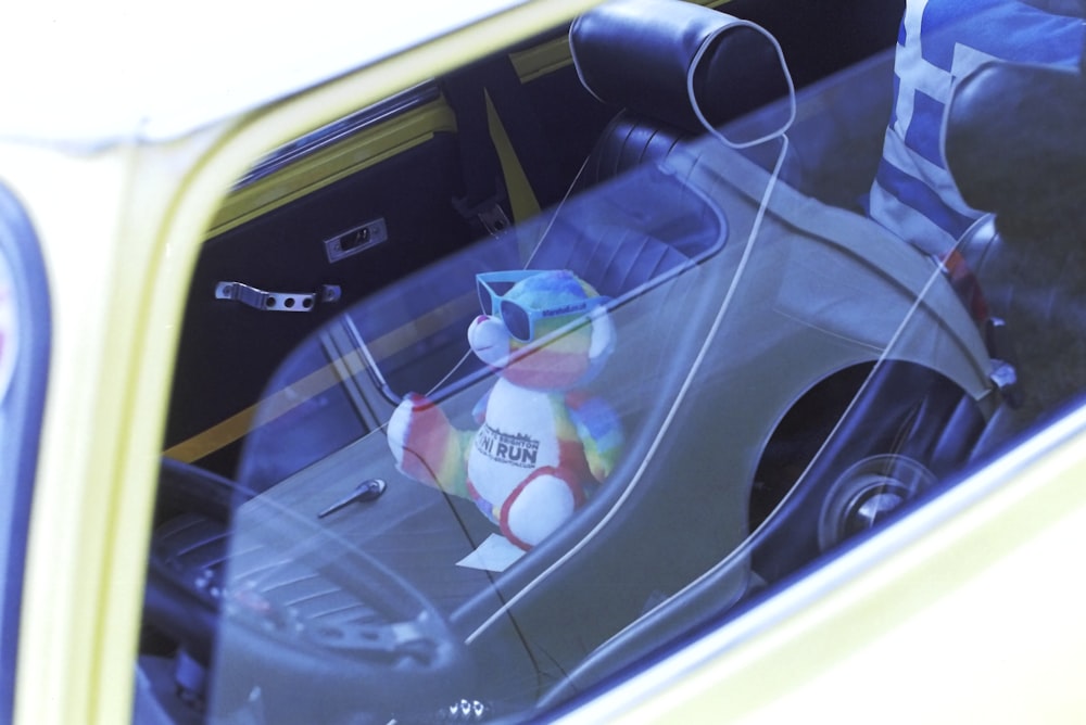 a teddy bear sitting in the back seat of a car