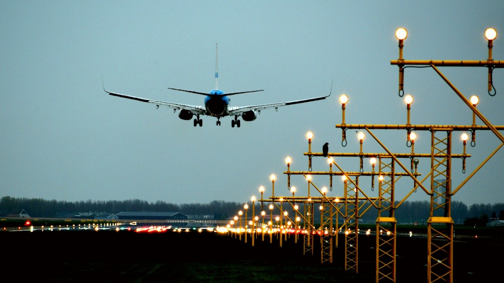 a large jetliner flying over a runway at night