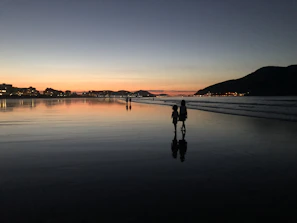 Couple walking along Ipanema beach with vibrant cityscape behind.