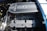 A detailed view of a car engine, prominently featuring a Ford Racing 427 Cobra engine with visible components such as the air filter, valves, and spark plug wires. The engine is clean and well-maintained, with metallic and mechanical parts showing intricate detailing.