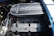 A detailed view of a car engine, prominently featuring a Ford Racing 427 Cobra engine with visible components such as the air filter, valves, and spark plug wires. The engine is clean and well-maintained, with metallic and mechanical parts showing intricate detailing.