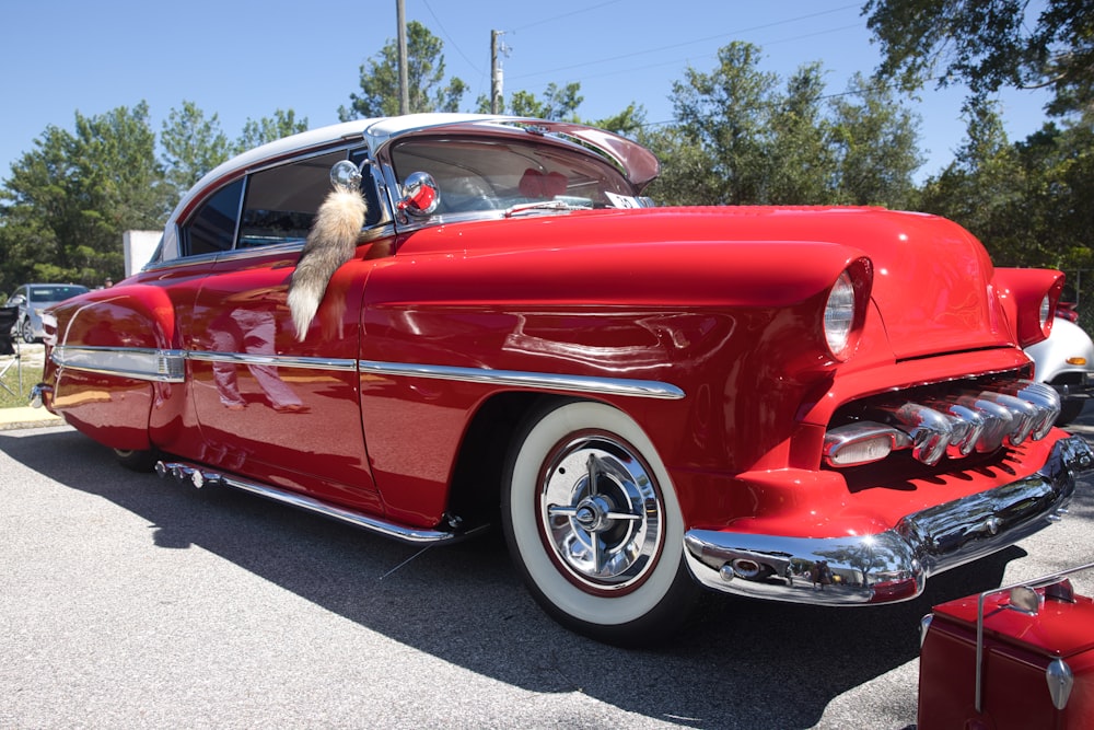 a red classic car parked in a parking lot