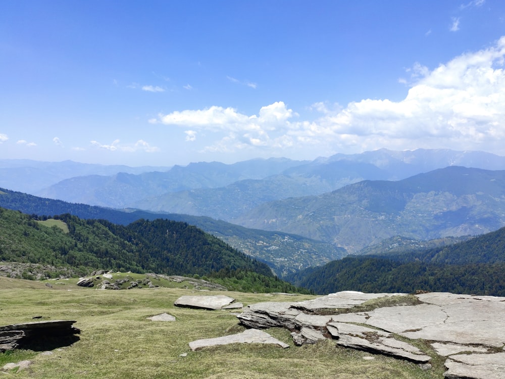 a view of a mountain range with a bench in the foreground