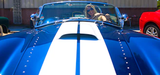 A happy driver standing next to their car after getting it back.