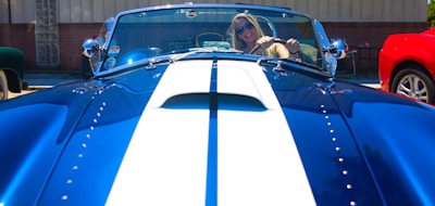 A sleek car parked with a smiling owner holding insurance documents.