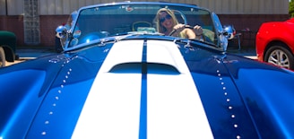 Smiling customer standing next to their car after the paint job.