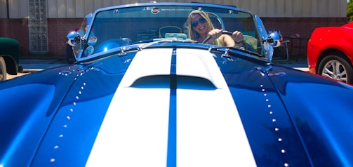 A smiling customer wearing a white t-shirt with their vintage blue car printed on it.