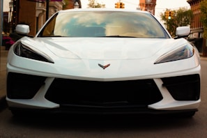 a white chevy corvette on michelin tyres parked infront of an auto store in nigeria