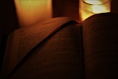 An open ancient scripture with a gentle candlelight glow, inviting reflection.