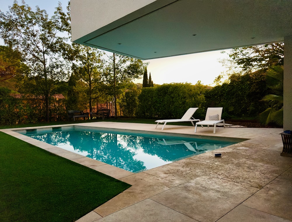 a swimming pool with a lawn and lawn chairs