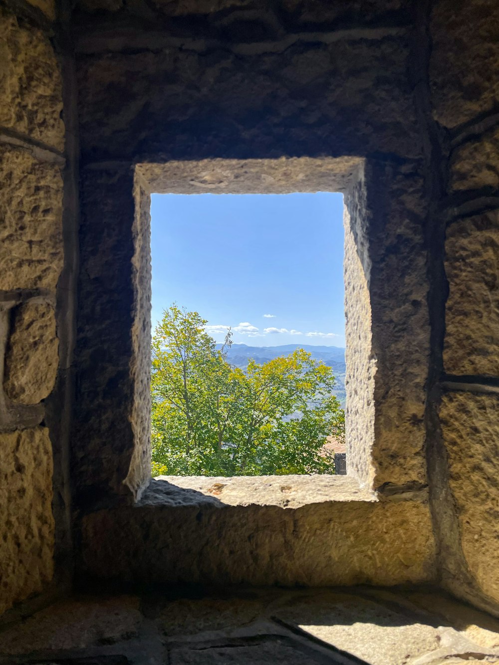 a window in a stone wall with a view of trees