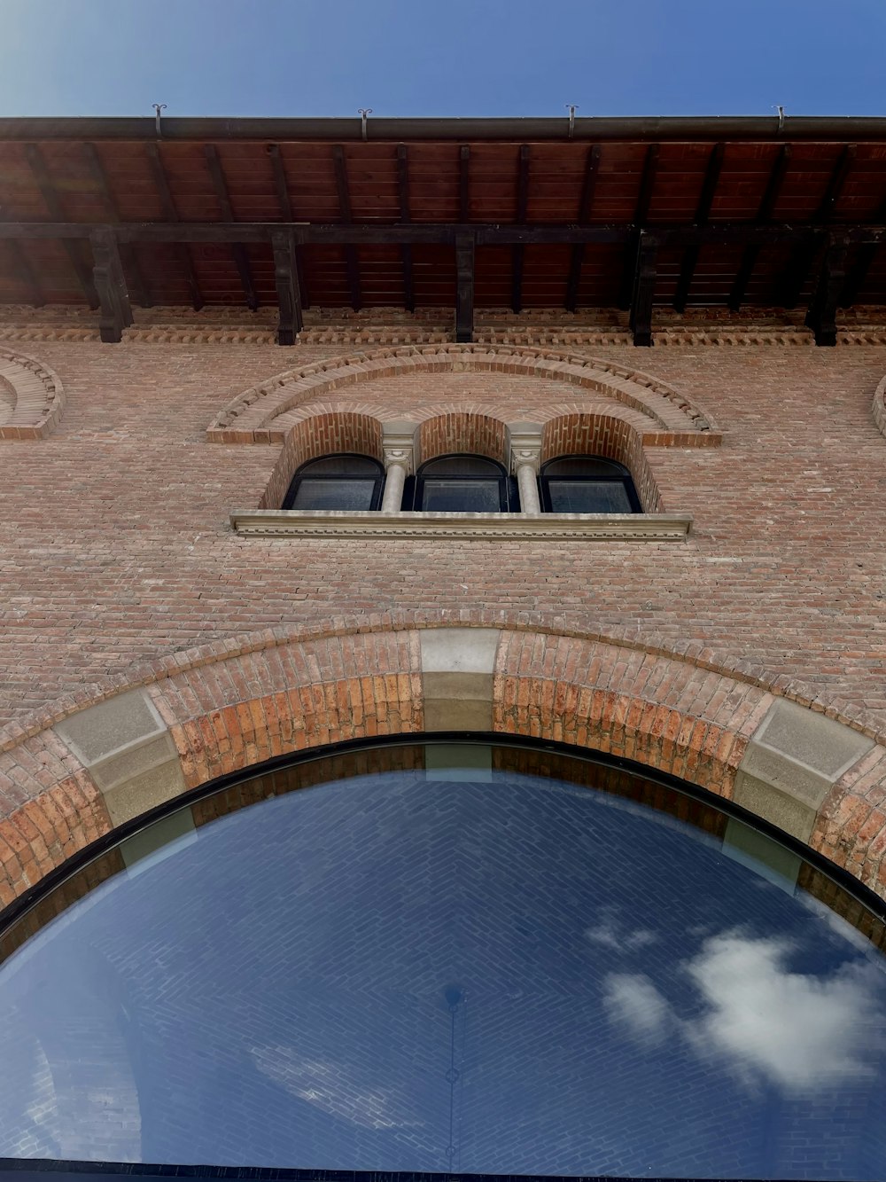 a brick building with arched windows and a sky background