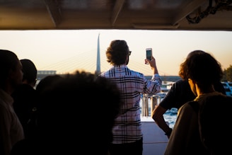 A group of friends laughing together on the boat’s deck, framed by the iconic 25 de Abril Bridge in the distance.