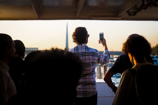A group of friends laughing together on the boat’s deck, framed by the iconic 25 de Abril Bridge in the distance.