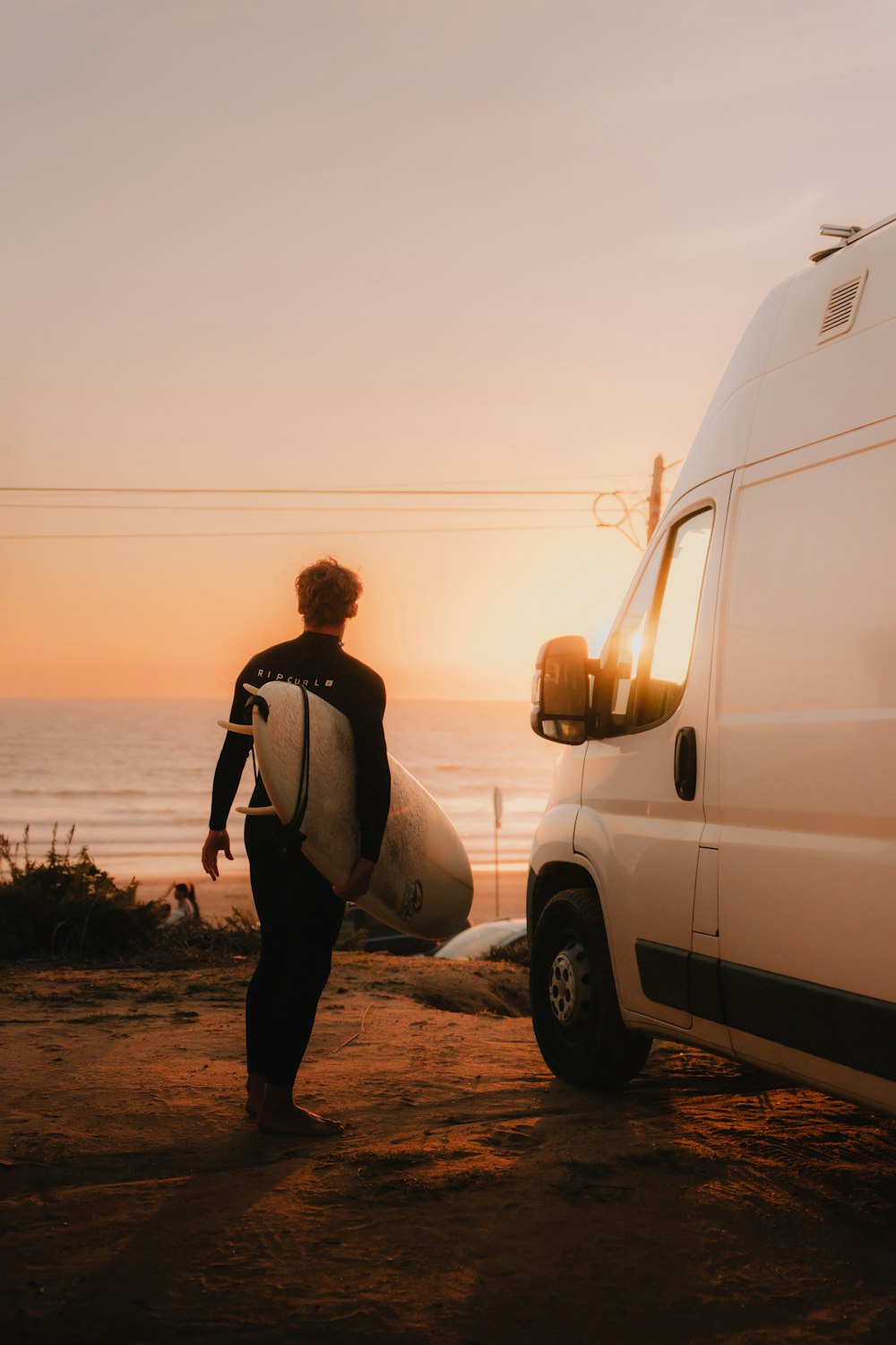 Un uomo che trasporta una tavola da surf accanto a un furgone