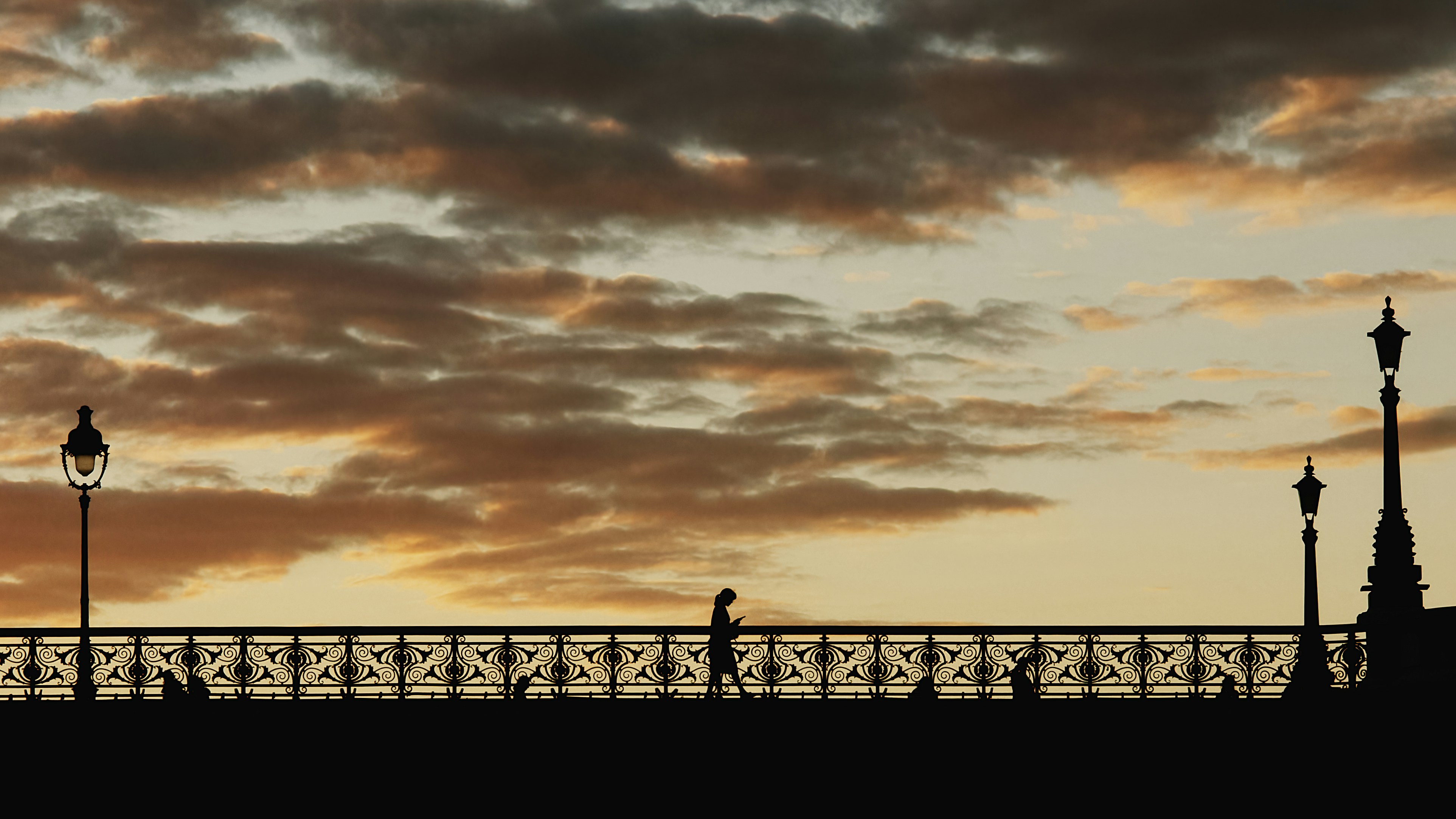 a person walking across a bridge at sunset