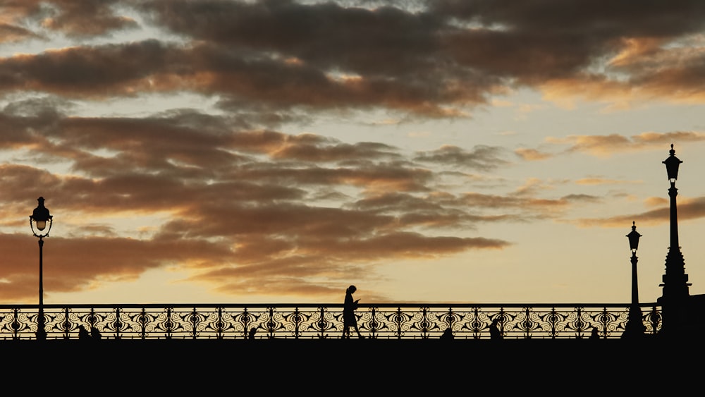 a person walking across a bridge at sunset