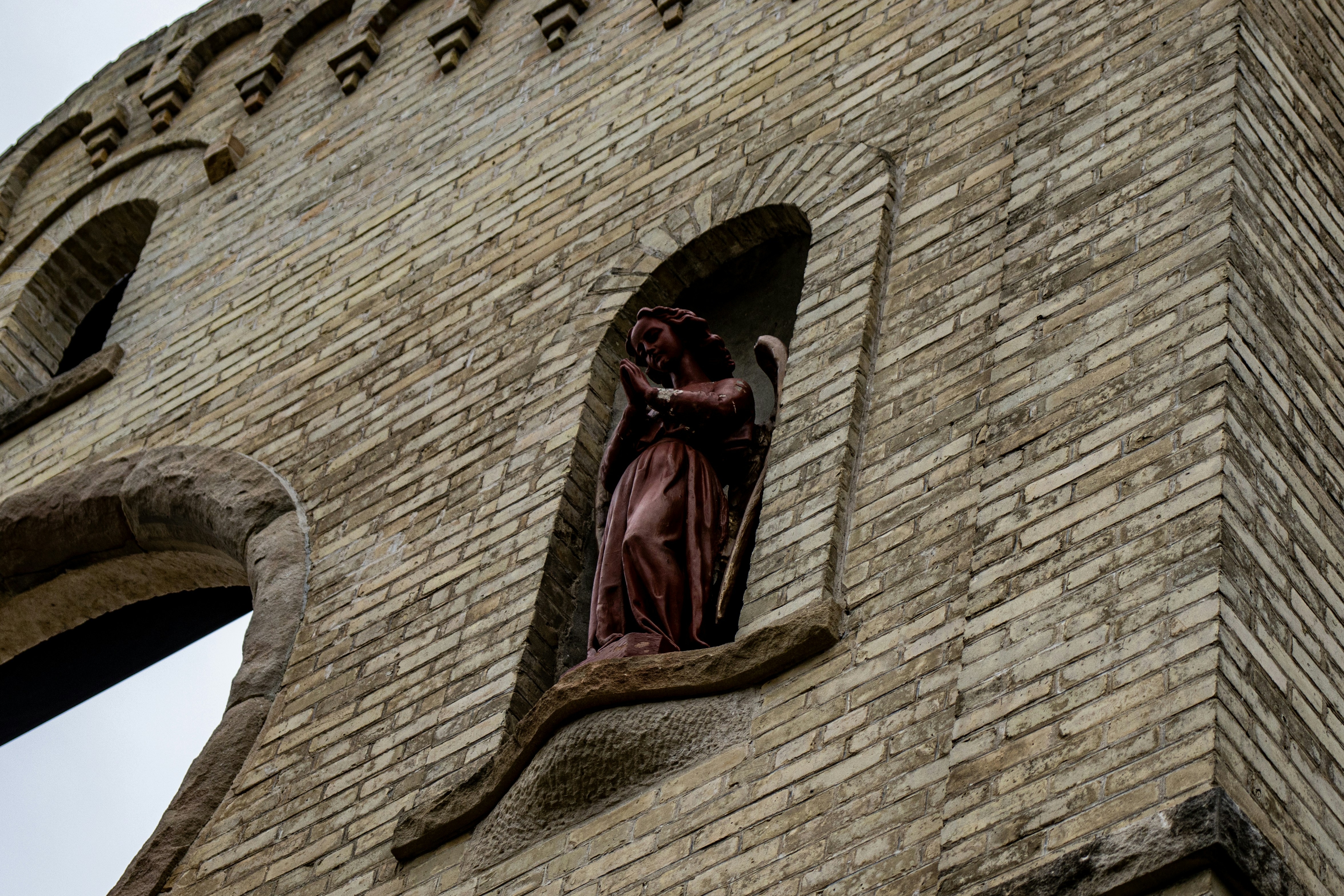 a statue of a woman in a window of a brick building, 