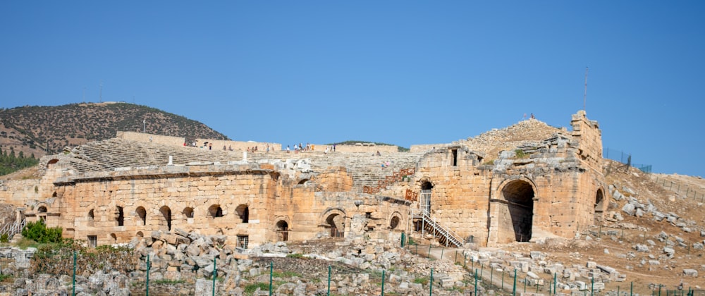 a stone building with a steep hill in the background