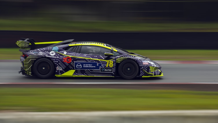 Abstract silhouette of a sleek supercar in motion with dynamic wing curves and a fiery red and orange blur background.