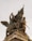 A detailed bronze sculpture depicts a group of figures with a sense of movement and action. One figure holds a flag, another brandishes a sword, and a winged lion is present. The texture and intricate details of the figures and the base are highlighted against the sky.