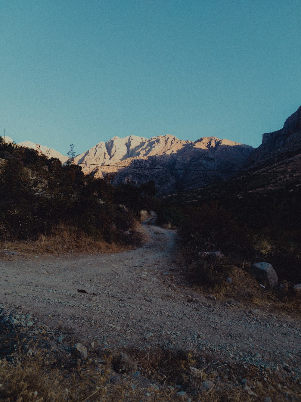 a dirt road with a mountain in the background